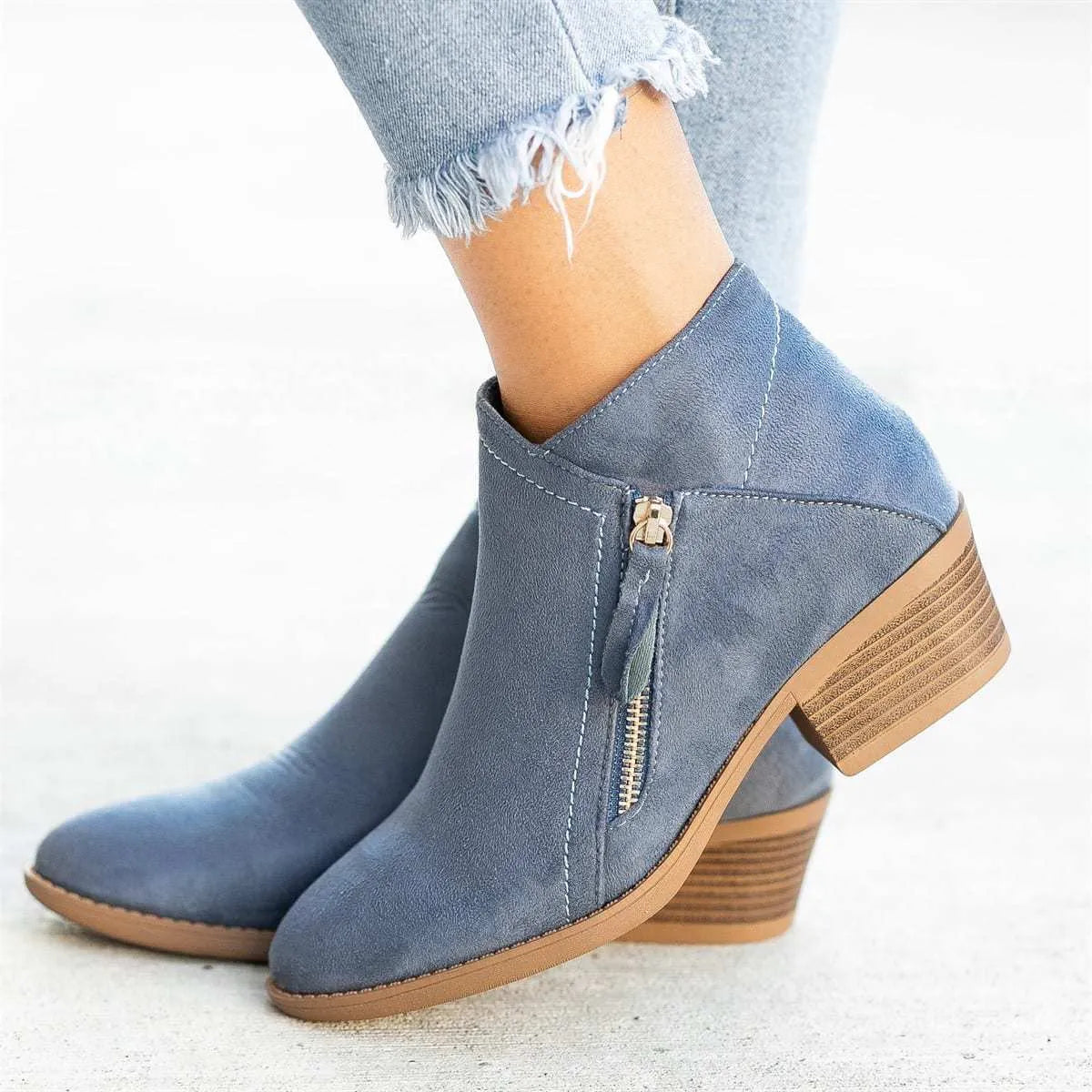 Women's blue suede Dr Martens ankle boots with side zip and chunky heel on a white background.