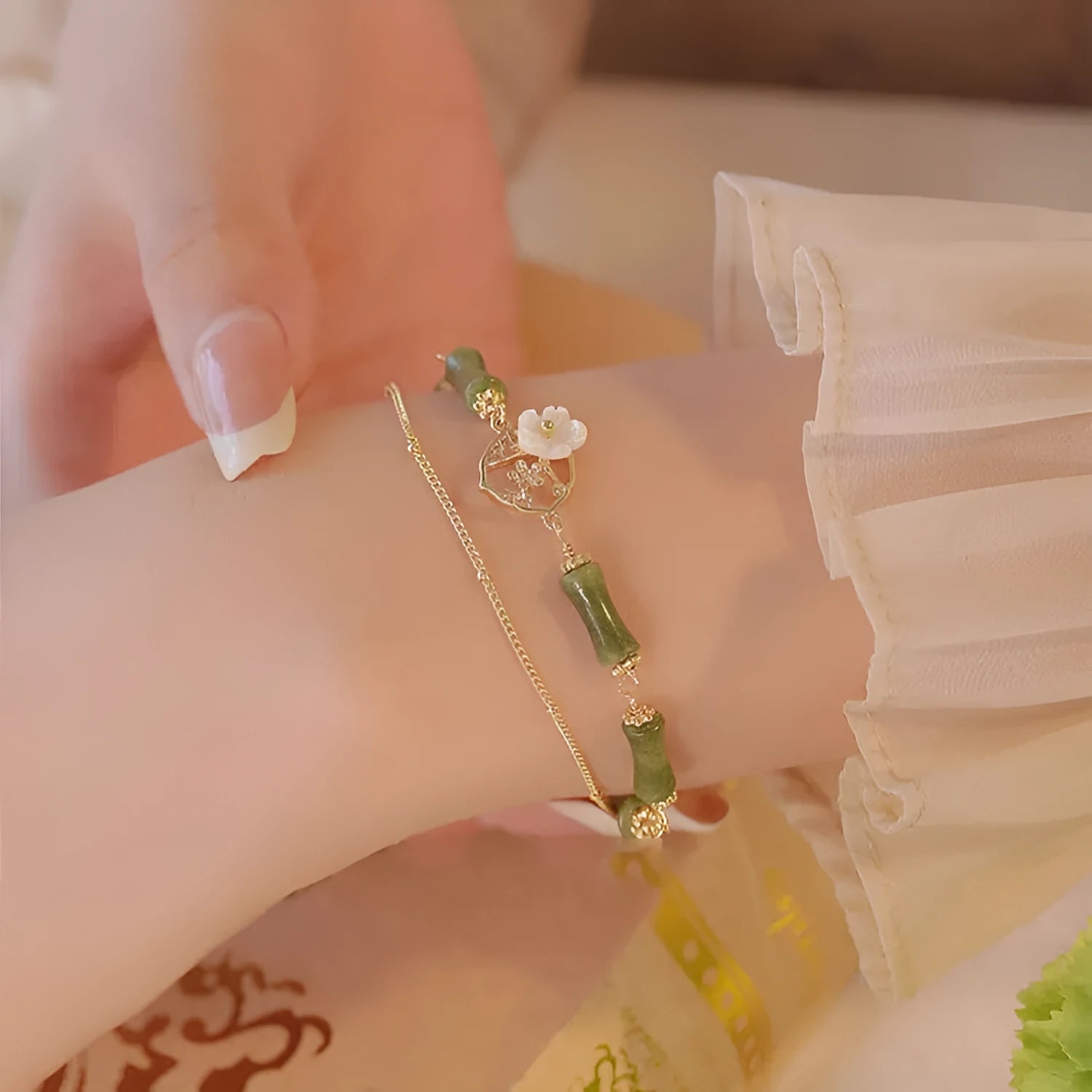 Natural olivine gemstone bracelet with double layers and twin Bells of Ireland charms on a wrist.