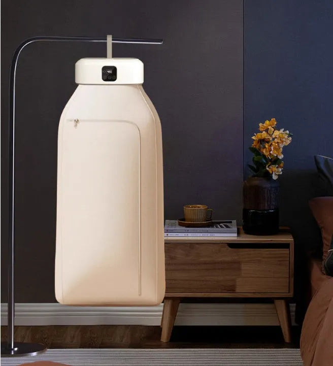 White cylindrical compact foldable laundry dryer with remote control on a table.