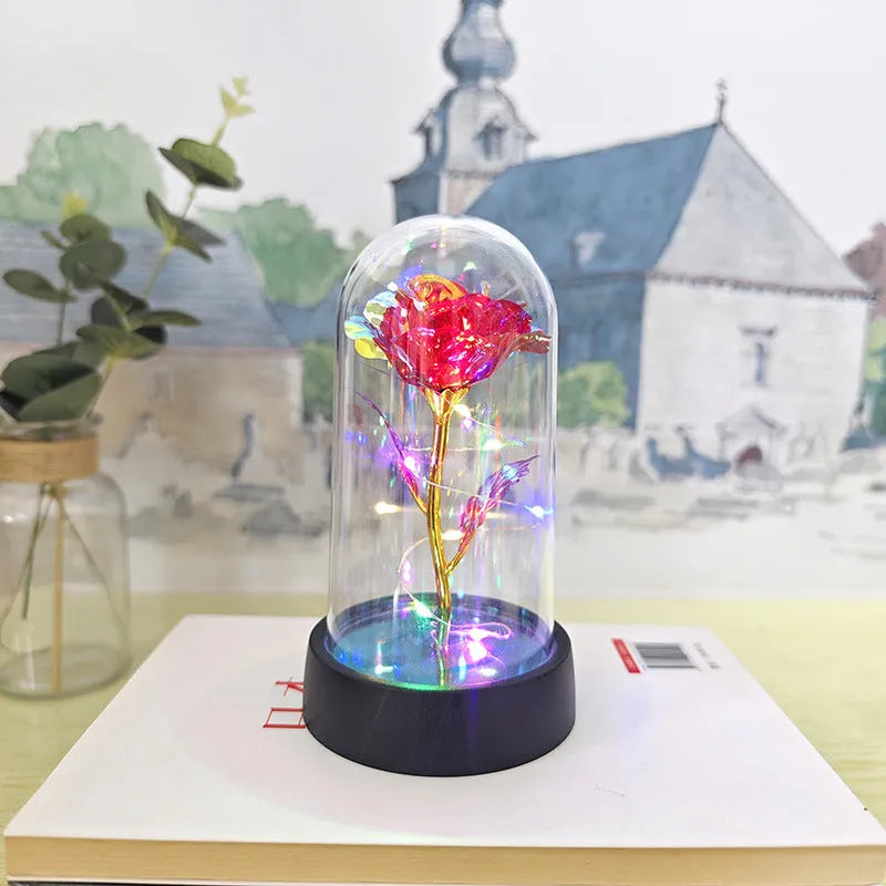 Small decorative night lamp with glass cover, plastic flower, and black base on a pink box.