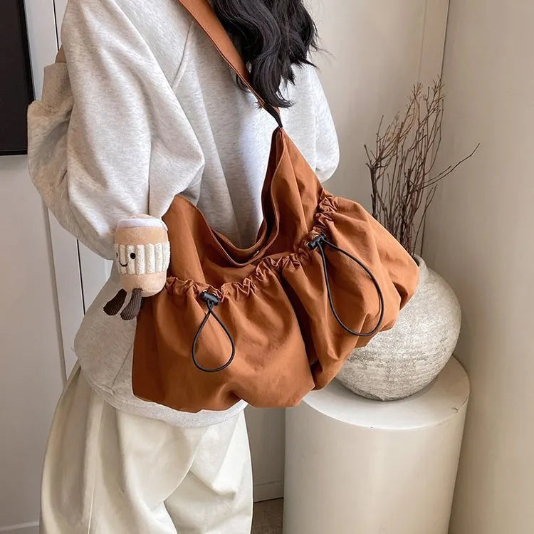 Ultra-light pleated foldable crossbody bag in beige, showing split pocket and crossbody strap.