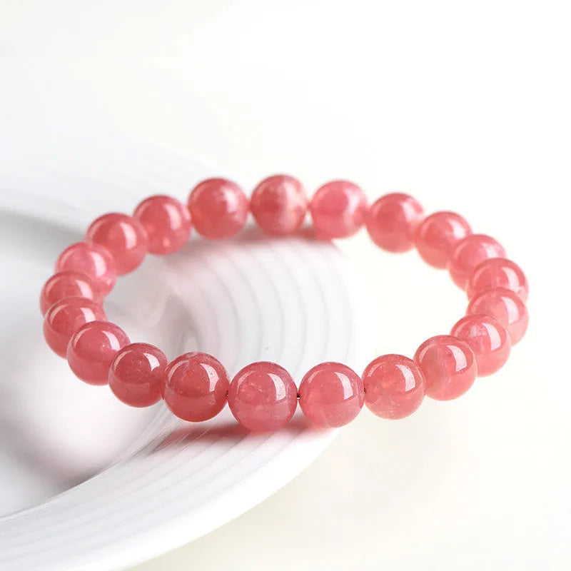 Women's geometric crystal bracelet with red rhodochrosite stone and a Longevity Lock charm on a wrist.