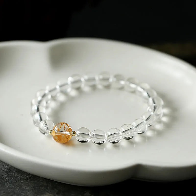 Geometric obsidian and white crystal beaded bracelet with golden dragon charm on a wrist.
