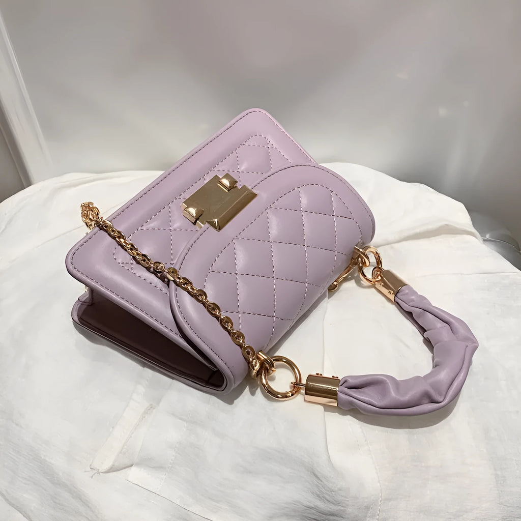 Small square purple shoulder bag with rhombus pattern showing crossbody strap and interior compartment.