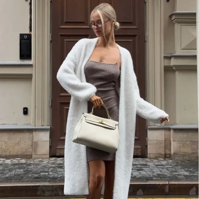 Long white knitted cardigan jacket with long sleeves on a hanger