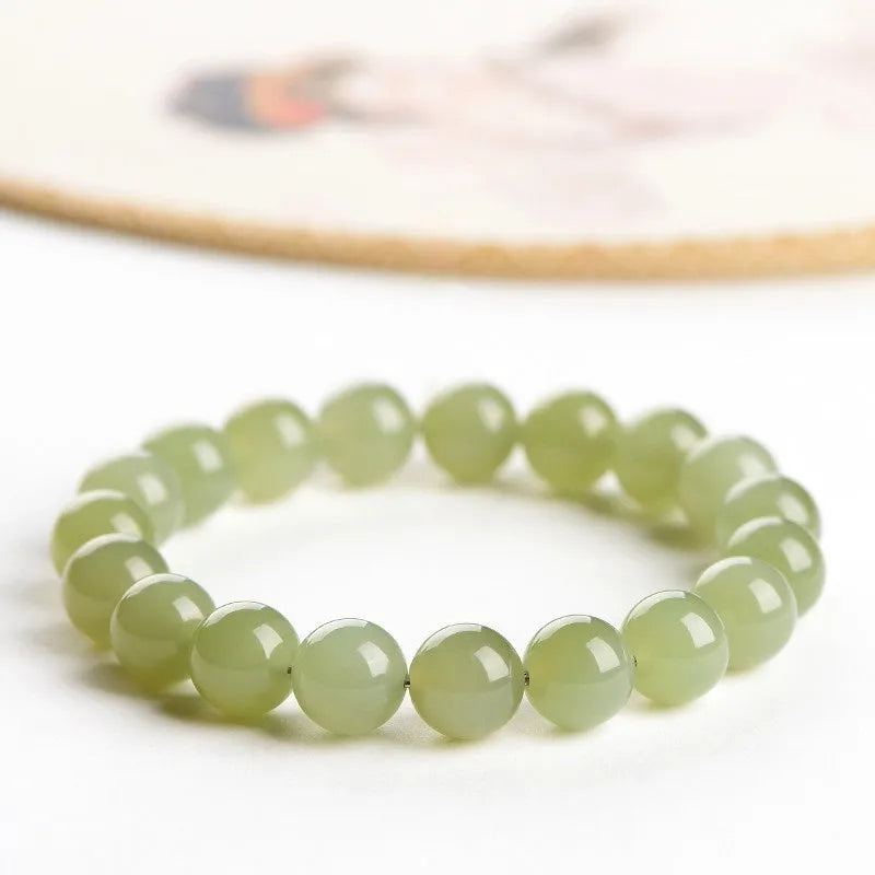 A polished Hetian Jade ball bracelet in a clear water colour on a wrist, showing spherical beads.