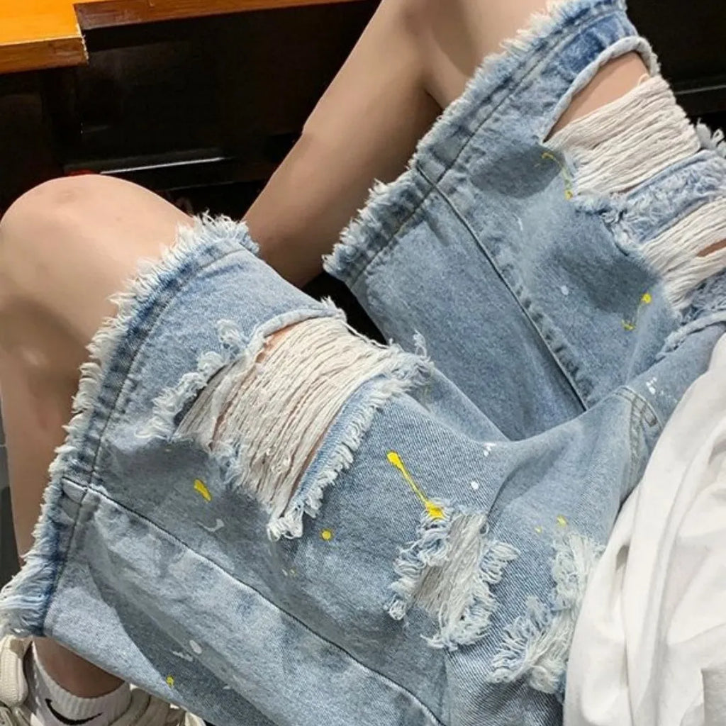Man wearing loose-fit light blue denim shorts with water-washed distressed fabric and a fifth pants length.