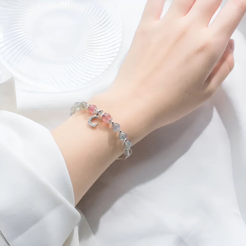 Adjustable natural moonstone bracelet with crescent moon charm on a wrist, showing extension chain.