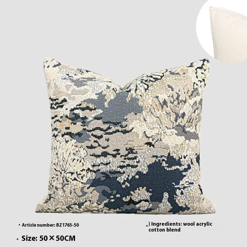 Blue decorative pillow with abstract flower pattern in 50x50cm square size on a grey sofa.