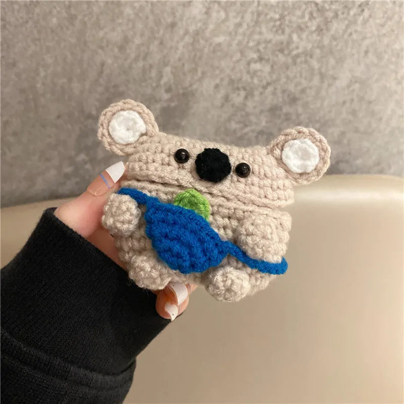 Handmade knitted koala bear backpack cover for Apple Airpods case on a table.