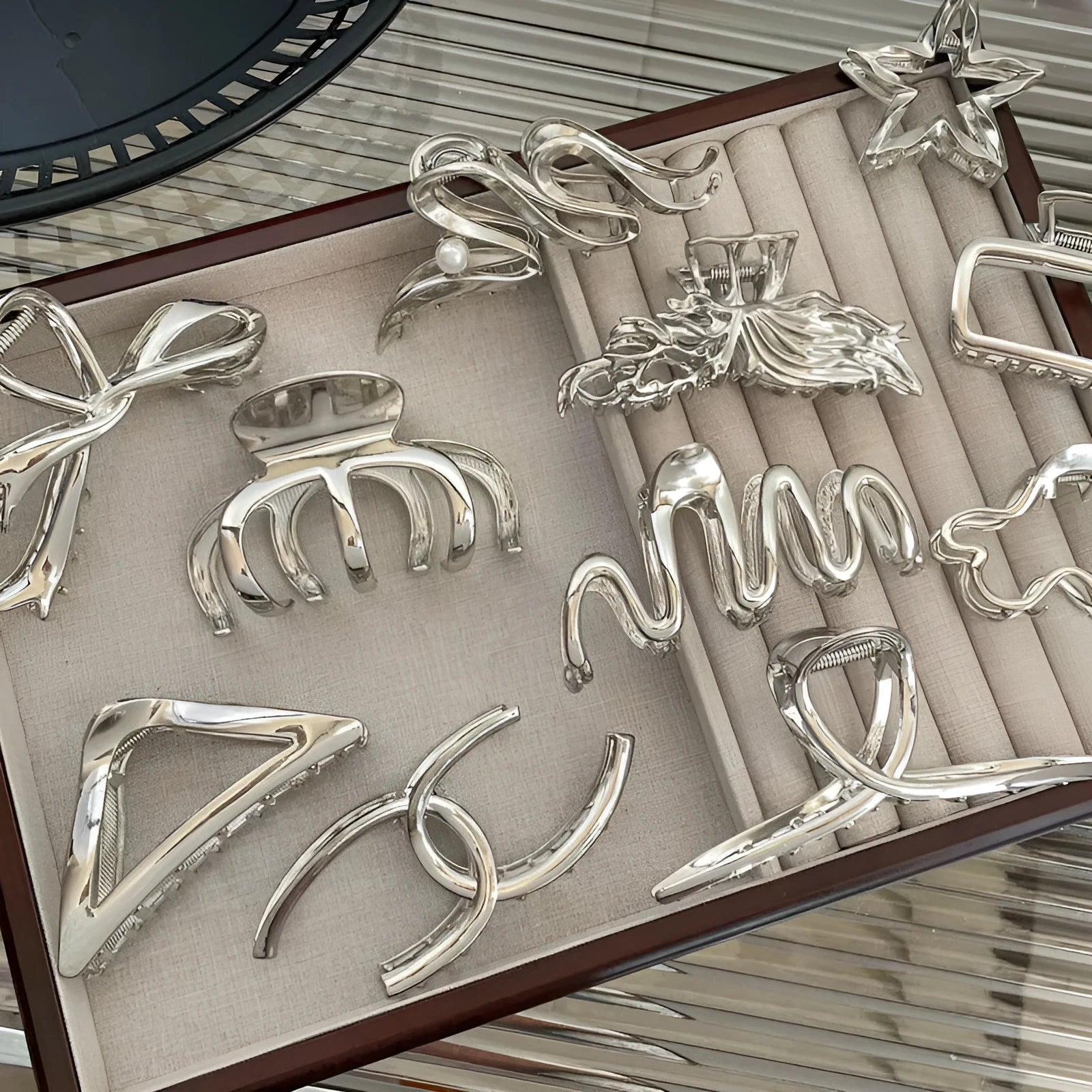 Assorted silver metal hair claws and barrettes including wave, knot, bow, and pearl designs on a white background.