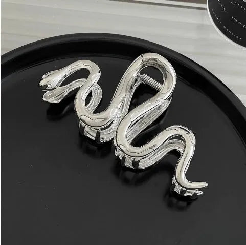 Assorted silver metal hair claws and barrettes including wave, knot, bow, and pearl designs on a white background.