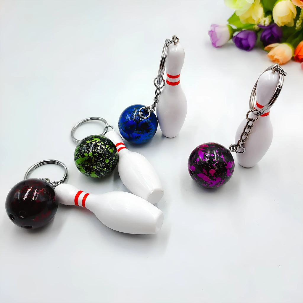 Miniature dark red bowling ball keychain on a metal key ring against a white background.
