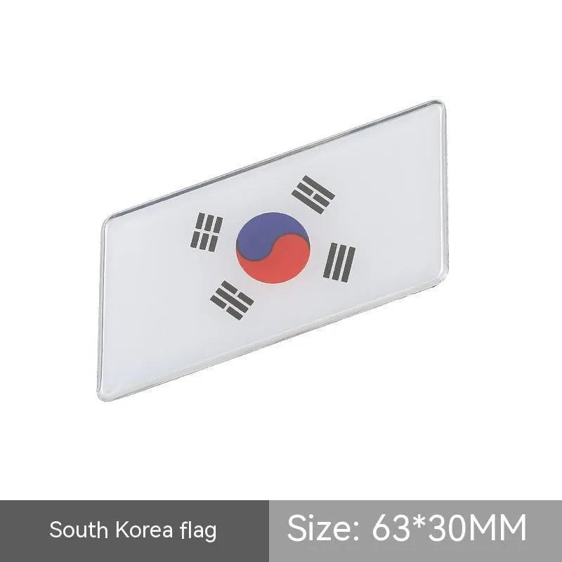 Aluminium parallelogram car sticker showing a national flag design, measuring 6.3 by 3 centimetres.