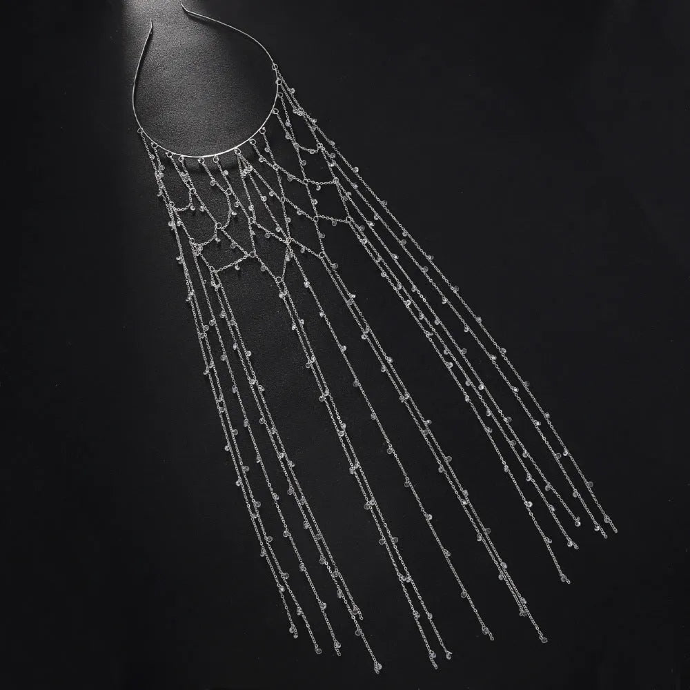 Gold rhinestone and mesh hairband with a long tassel, laid flat on a dark surface.