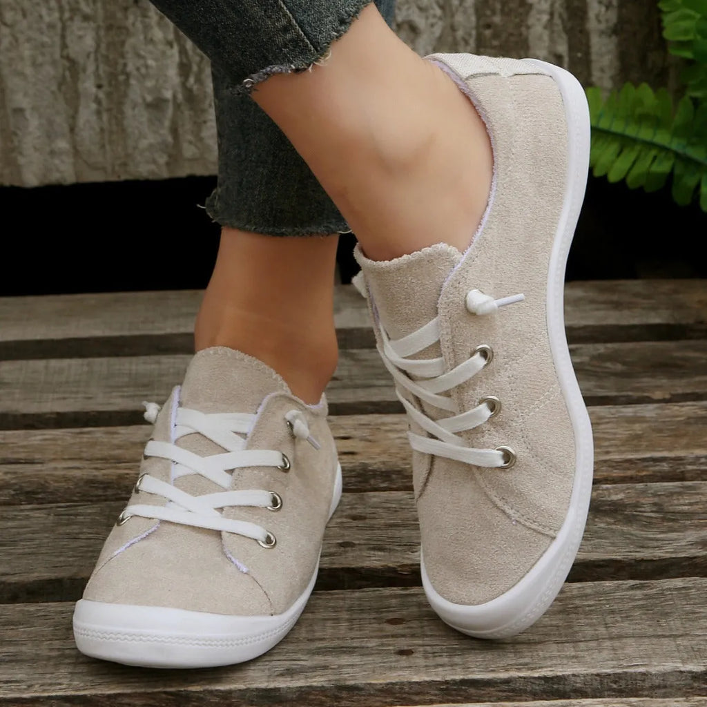 Women's creamy-white low-top fabric sneaker with rubber sole on a neutral background.
