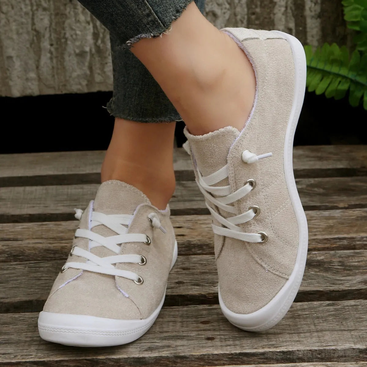 Women's creamy-white low-top fabric sneaker with rubber sole on a neutral background.