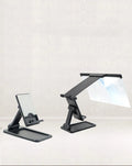 Black folding mobile phone screen magnifier with detachable phone holder on a desk.