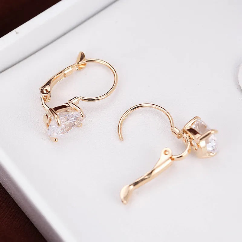 A pair of women's drop-shaped fashion earrings in gold or platinum finish with a platinum-inlaid gemstone.
