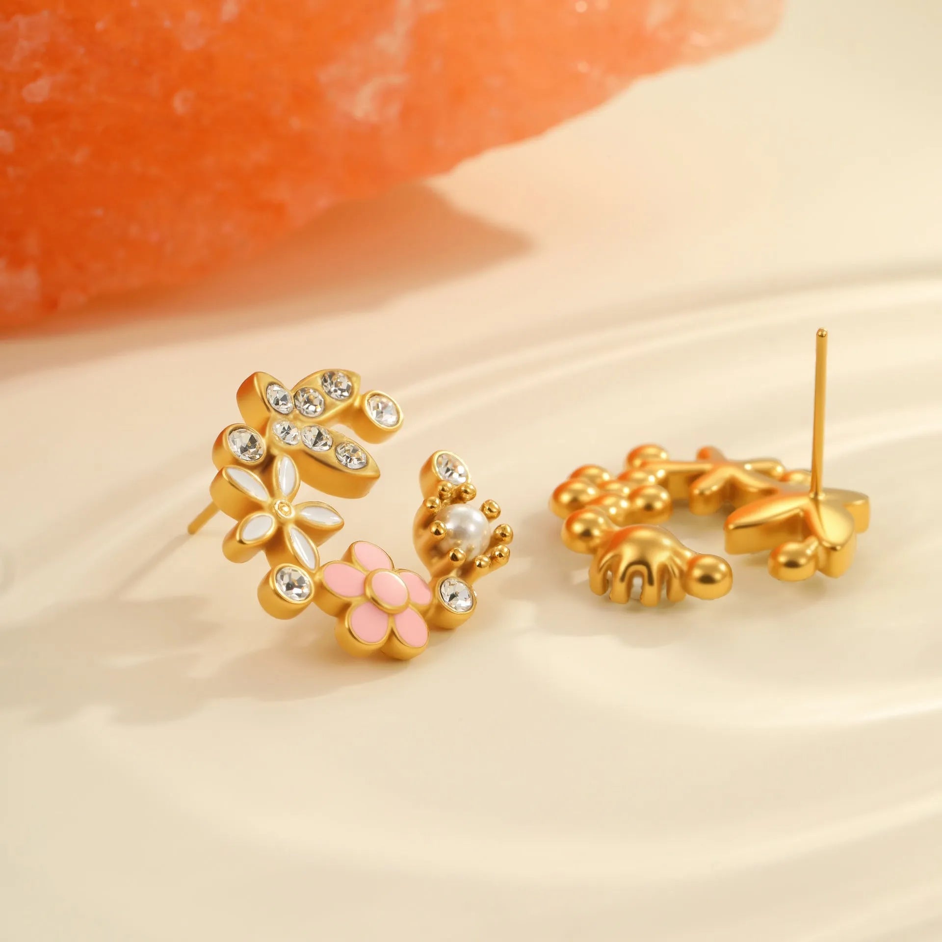 Close-up of colourful oil finish flower-shaped stud earrings with petal details on a stainless steel post.