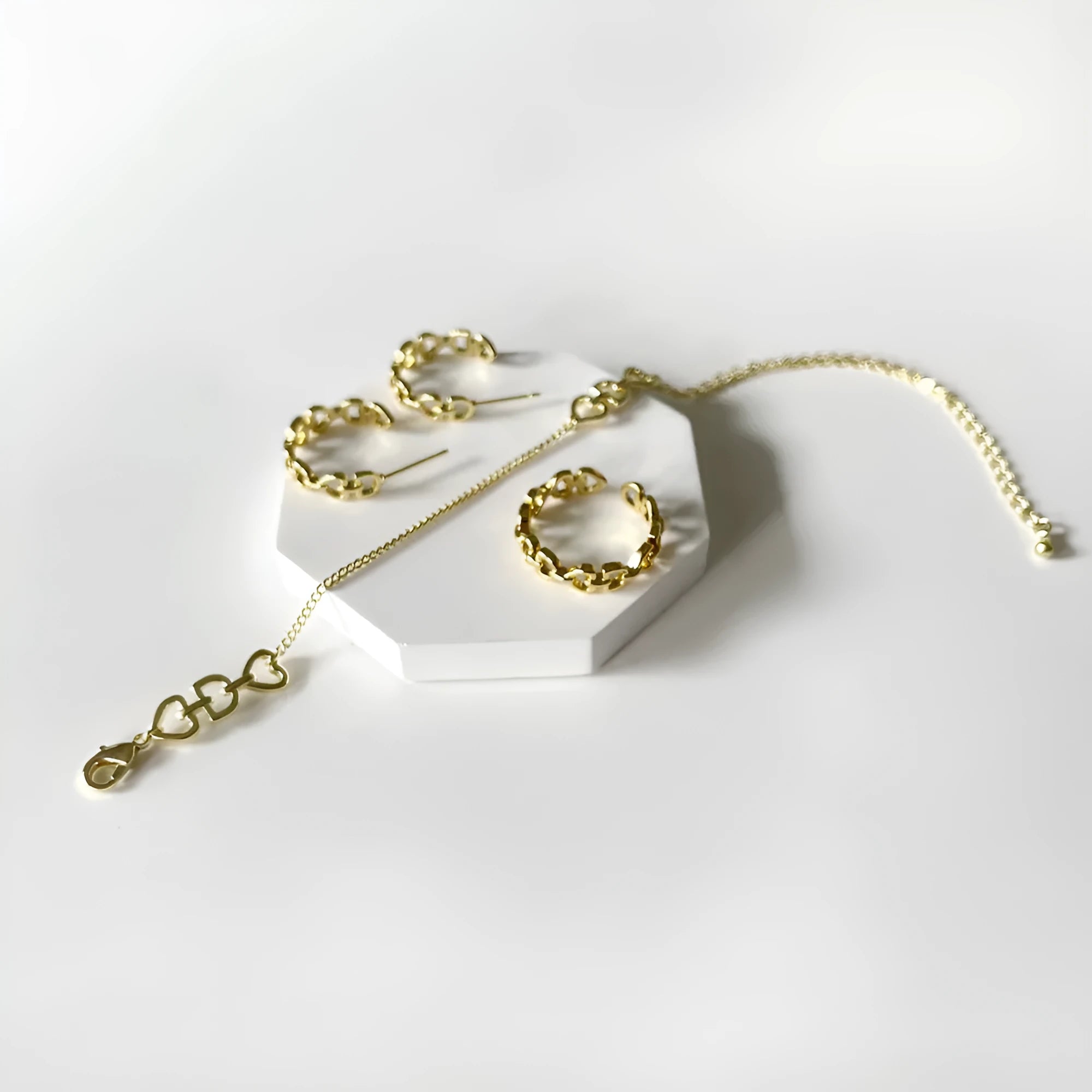 Minimalist Love Letter D geometric jewellery set including gold-plated earrings, ring, and bracelet on a light background