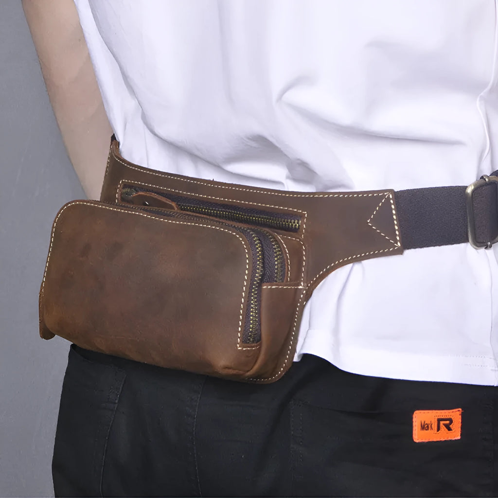 Brown cowhide leather men's sports waist bag with pull closure, shown with phone and laptop compartments.