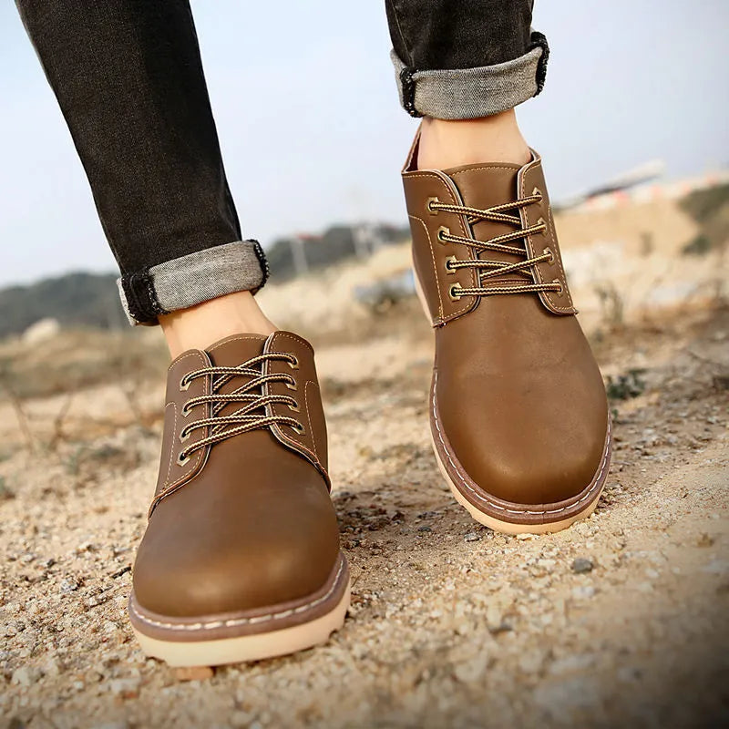 Men's mid-top black waterproof leather boots with non-slip rubber sole on flat surface