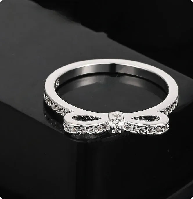 Silver electroplated ring with a detailed bow shape and set zircon crystal accents.