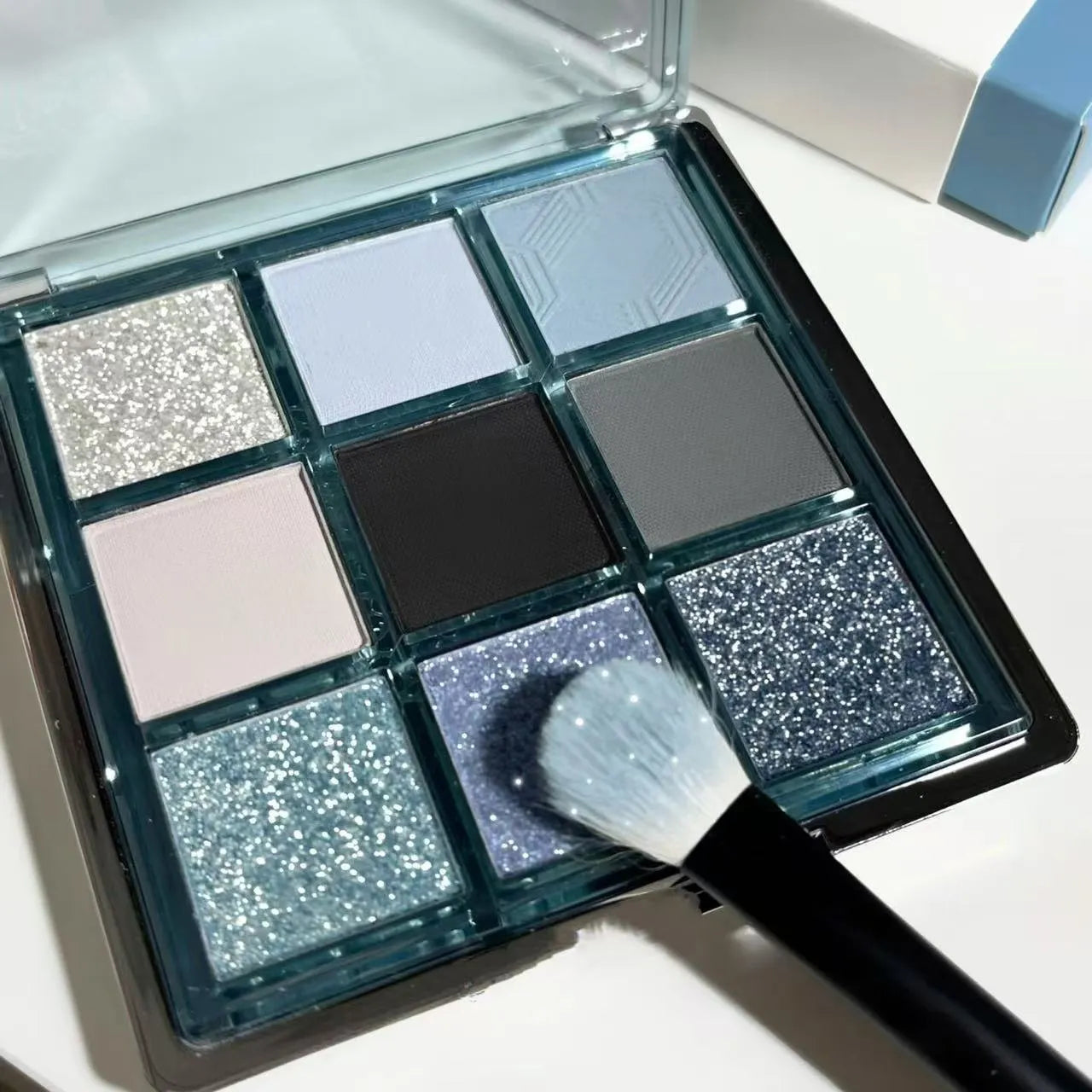 MUGELEEN nine-colour eye shadow palette showing matte and shimmer finishes in blue and smoked tones