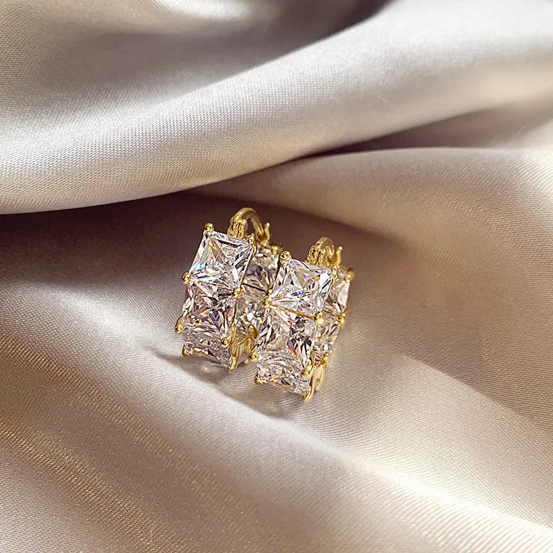 Geometric U-shaped gold-tone earrings with black zircon stones, approximately 20mm diameter