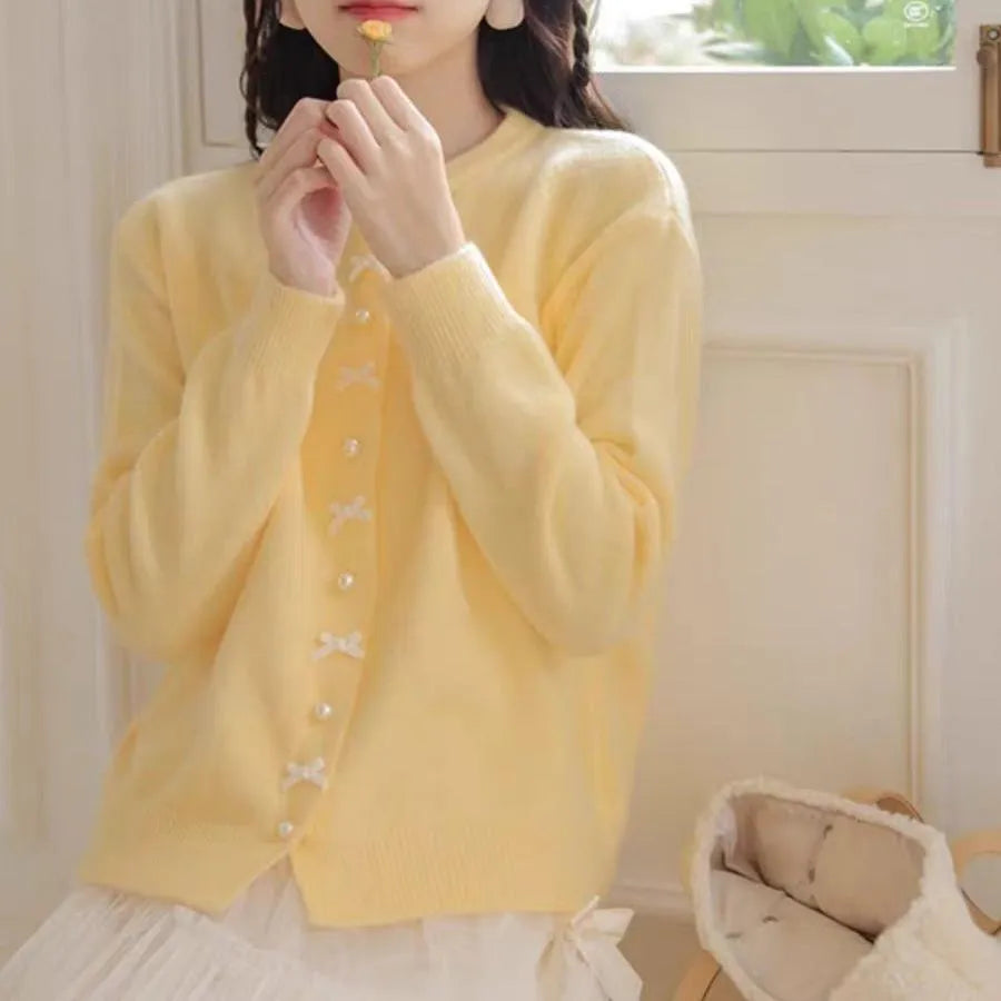 Women's solid colour cardigan with bow and pearl buttons, cashmere acrylic blend, shown in multiple colour options.