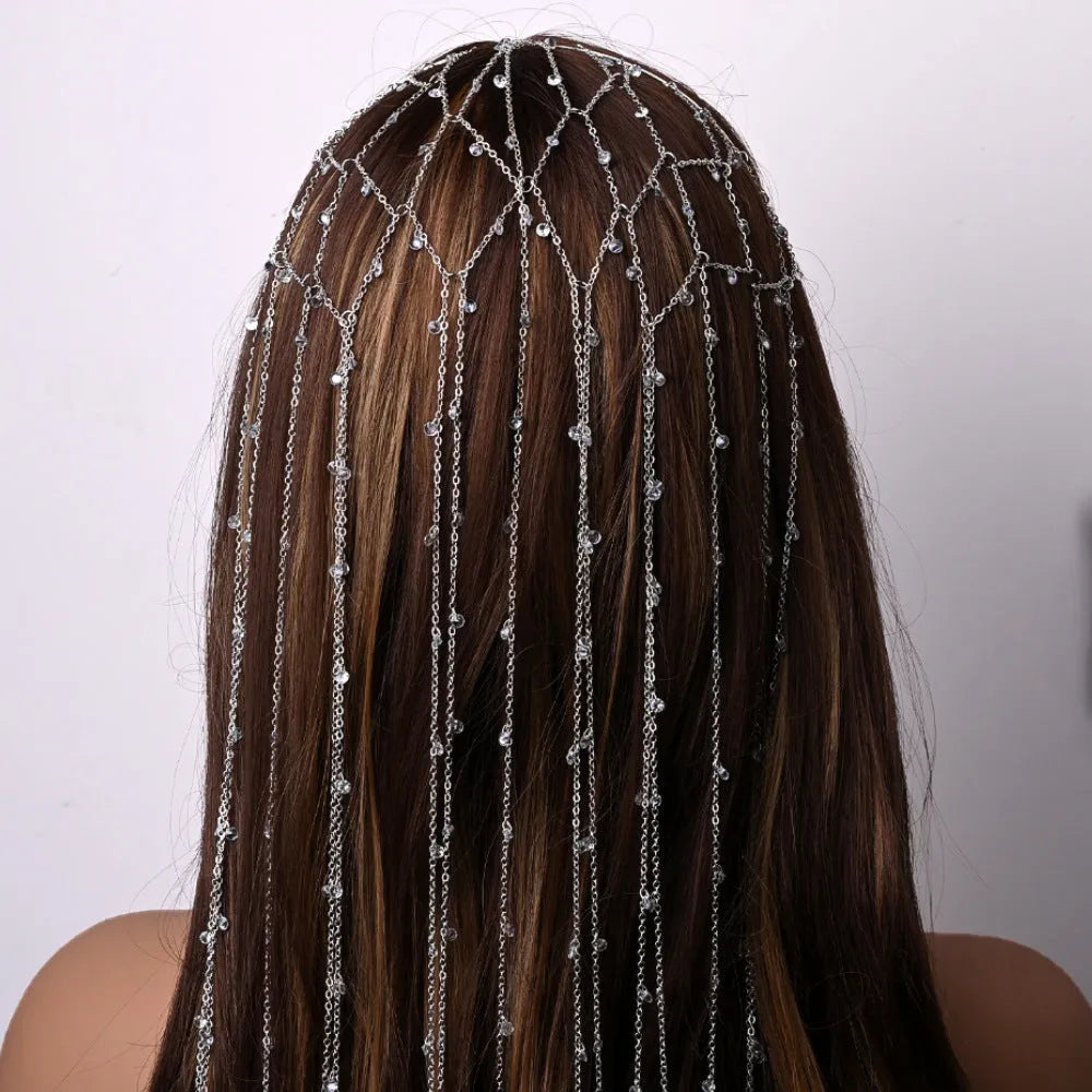 Gold rhinestone and mesh hairband with a long tassel, laid flat on a dark surface.
