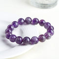 Natural feather amethyst crystal bracelet with scattered purple beads on a white background.