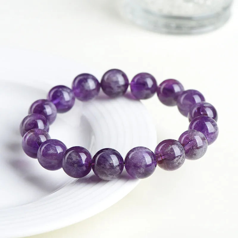 Natural feather amethyst crystal bracelet with scattered purple beads on a white background.