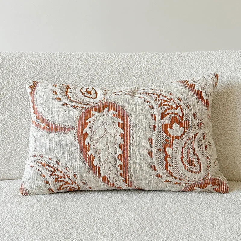 American-style jacquard pillow cover with paisley and flower pattern in amber colour, shown on a sofa.