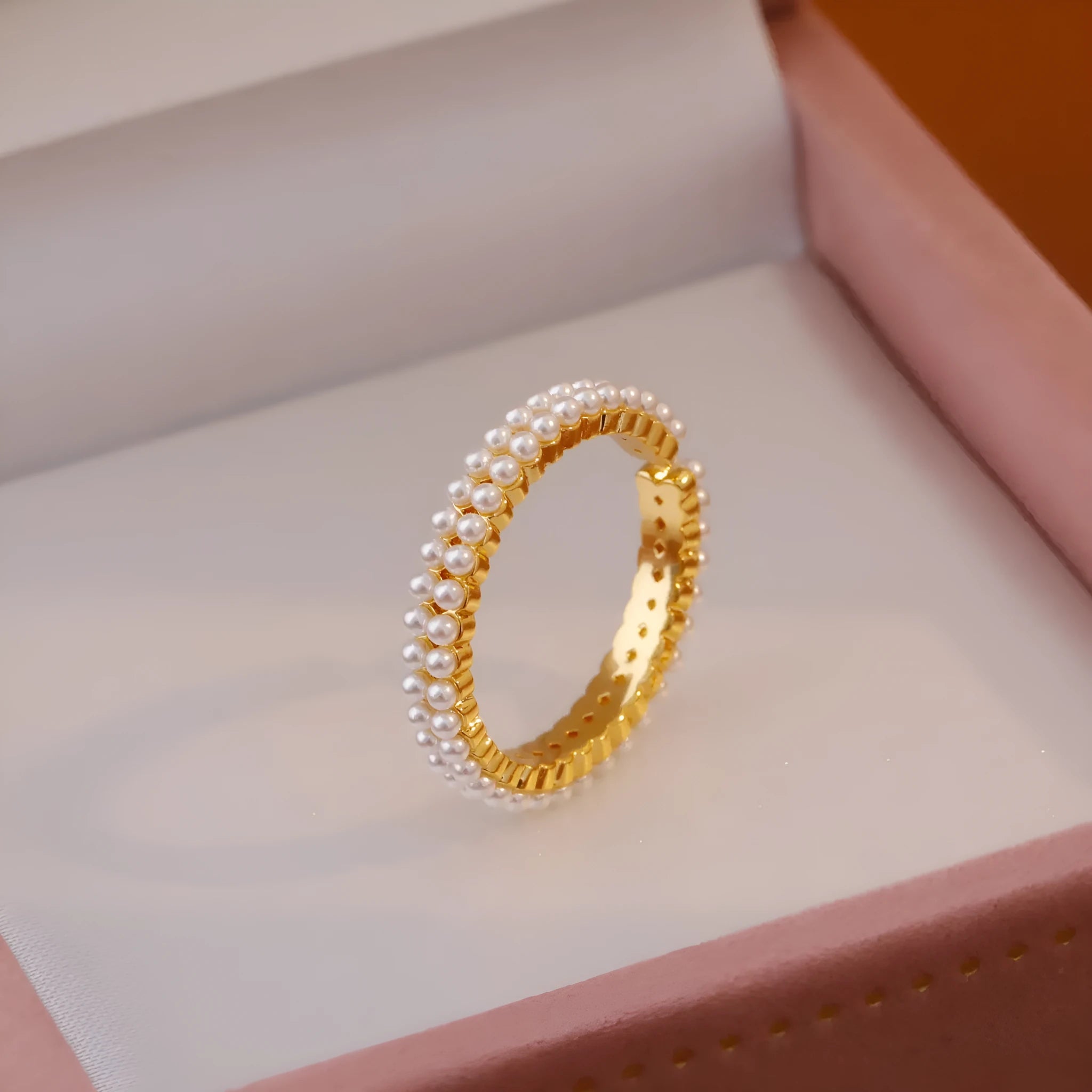 Gold electroplated open mouth geometry pearl ring for women on a neutral background.