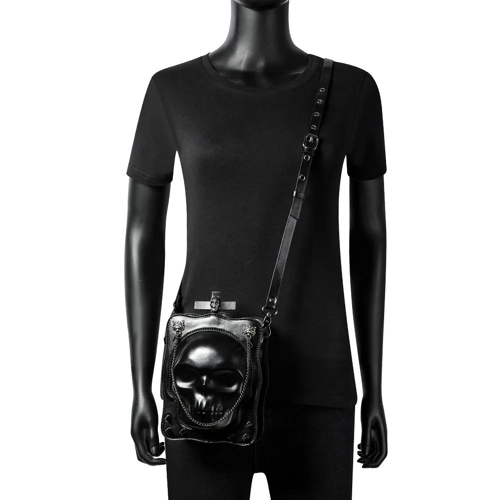 Black Gothic skull crossbody bag with embossed design, square shape, and chain detailing