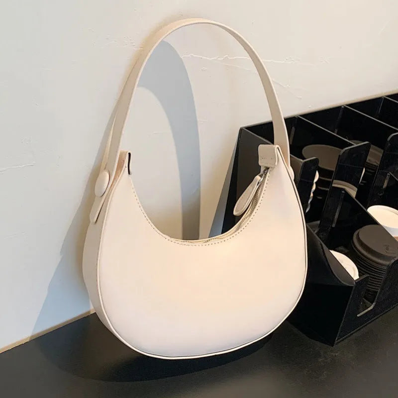 Women's retro dumpling-shaped PU leather shoulder bag in black showing sandwich pockets and zippered compartment