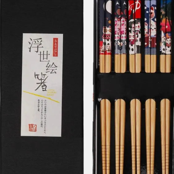 Set of five pairs of bamboo chopsticks with Japanese lucky cat and elegant blue patterns on a table.