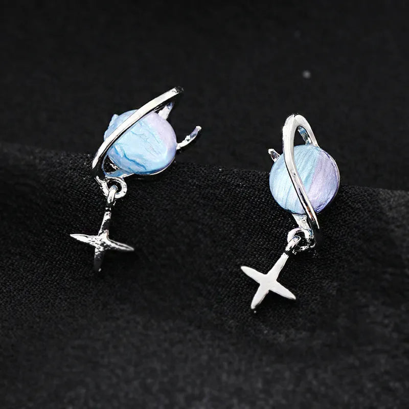 Metal geometric planet earrings in multicolour finish on a neutral background