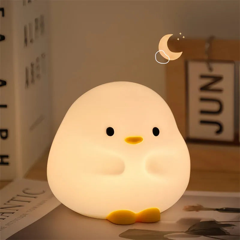 Cute duck-shaped silicone LED night lamp on a bedside table with warm light