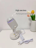 Dynamic water ripple projection table lamp with metal holder on a desktop.