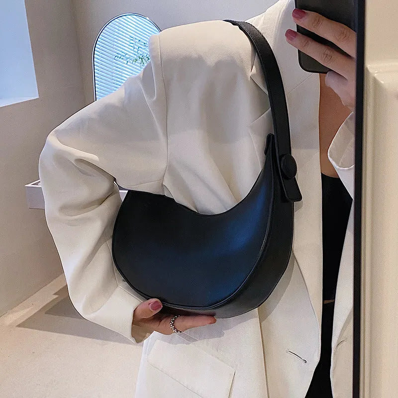 Women's retro dumpling-shaped PU leather shoulder bag in black showing sandwich pockets and zippered compartment