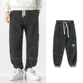 Men's loose-fit tapered cotton trousers in black showing tapered leg and mid-waist design