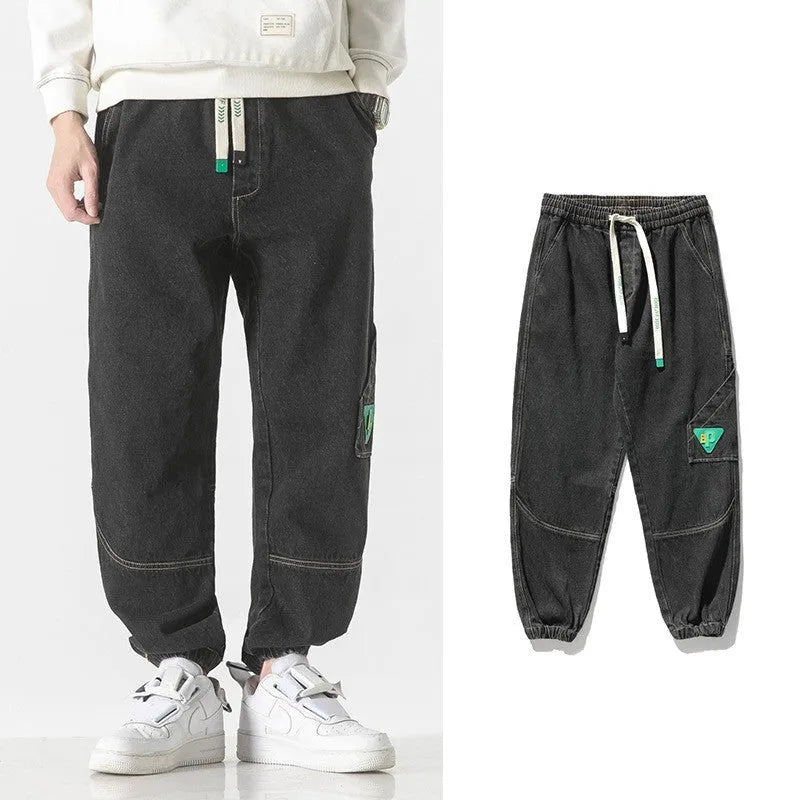 Men's loose-fit tapered cotton trousers in black showing tapered leg and mid-waist design