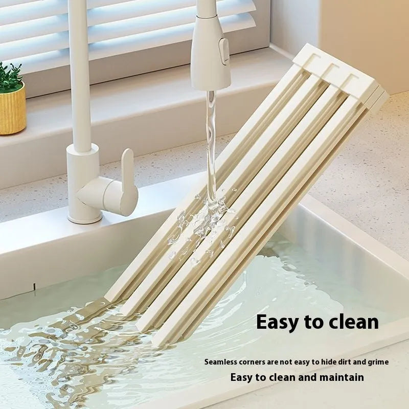 Milky white foldable stainless steel kitchen draining rack shown in a sink.