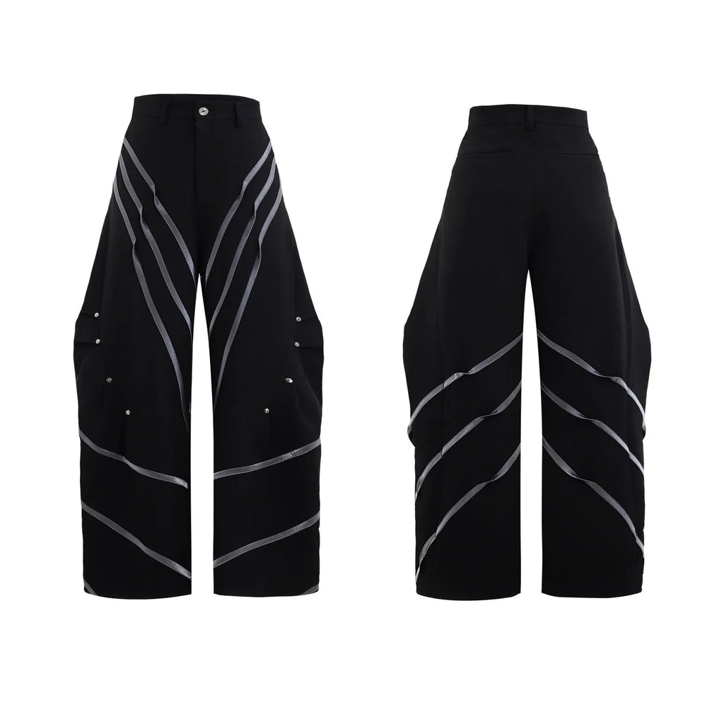 Men's black and white deconstructed trousers with metal striped rivets and front pleats.