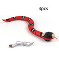Smart sensing interactive electronic snake cat toy on a floor, showing segmented plastic body and USB charging port.