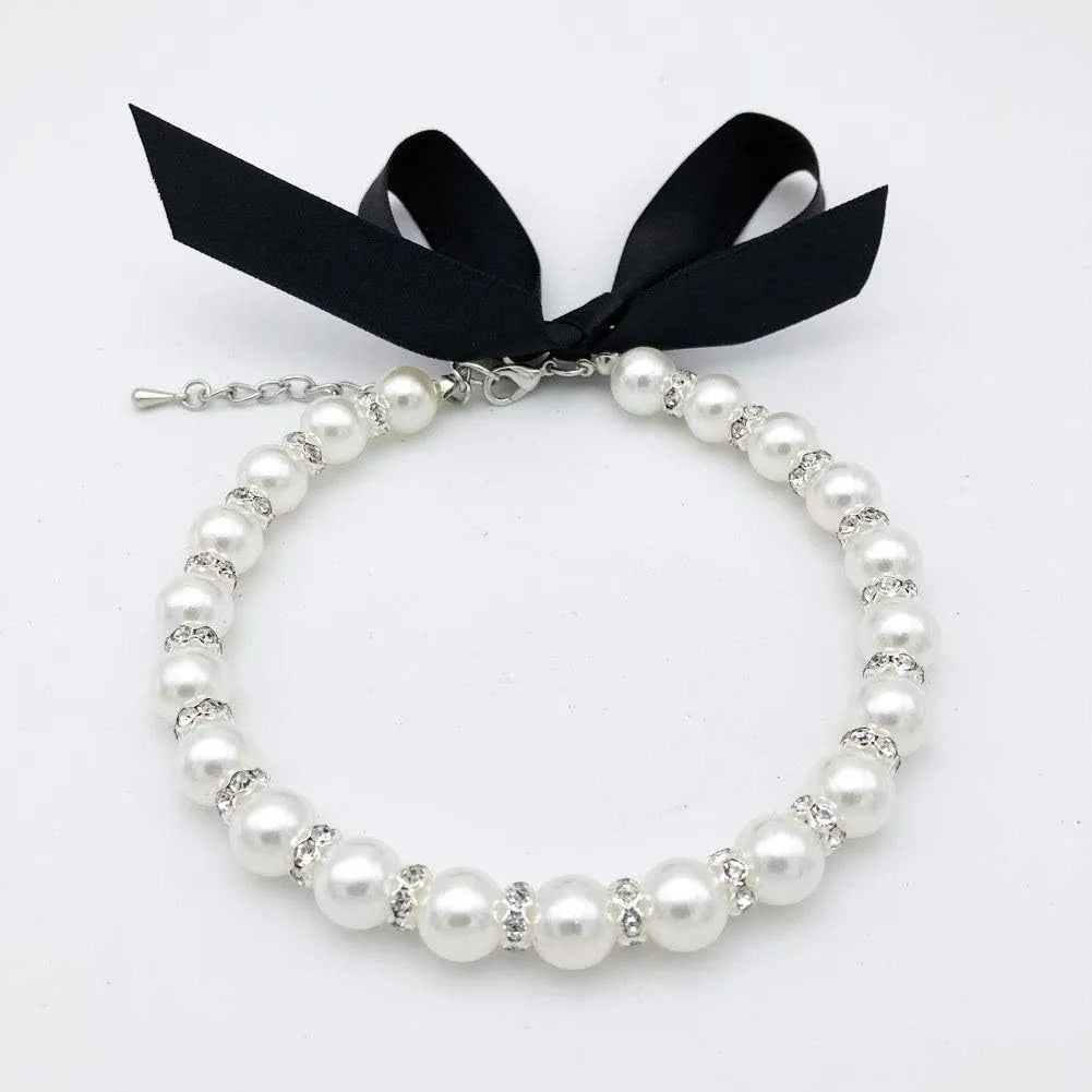 Small dog wearing adjustable pearl and rhinestone necklace with ribbon bow in pink colour