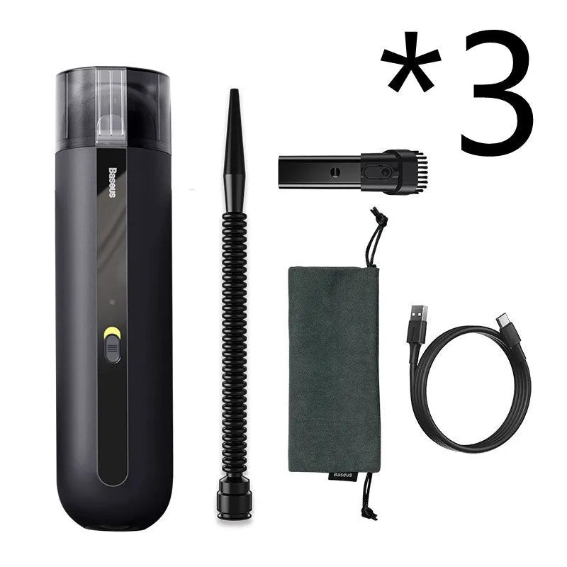 Black cordless handheld car vacuum cleaner with blowing hose attachment on a desktop.